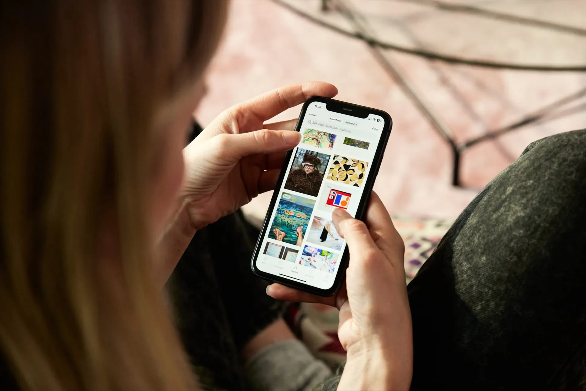 A woman browsing artworks in the Atelie app on her phone.